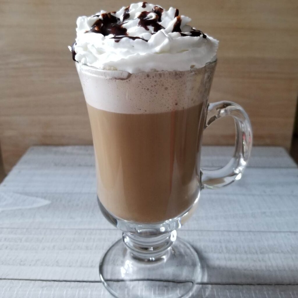 chocolate hazelnut latte in a cup with whipped cream and chocolate drizzle