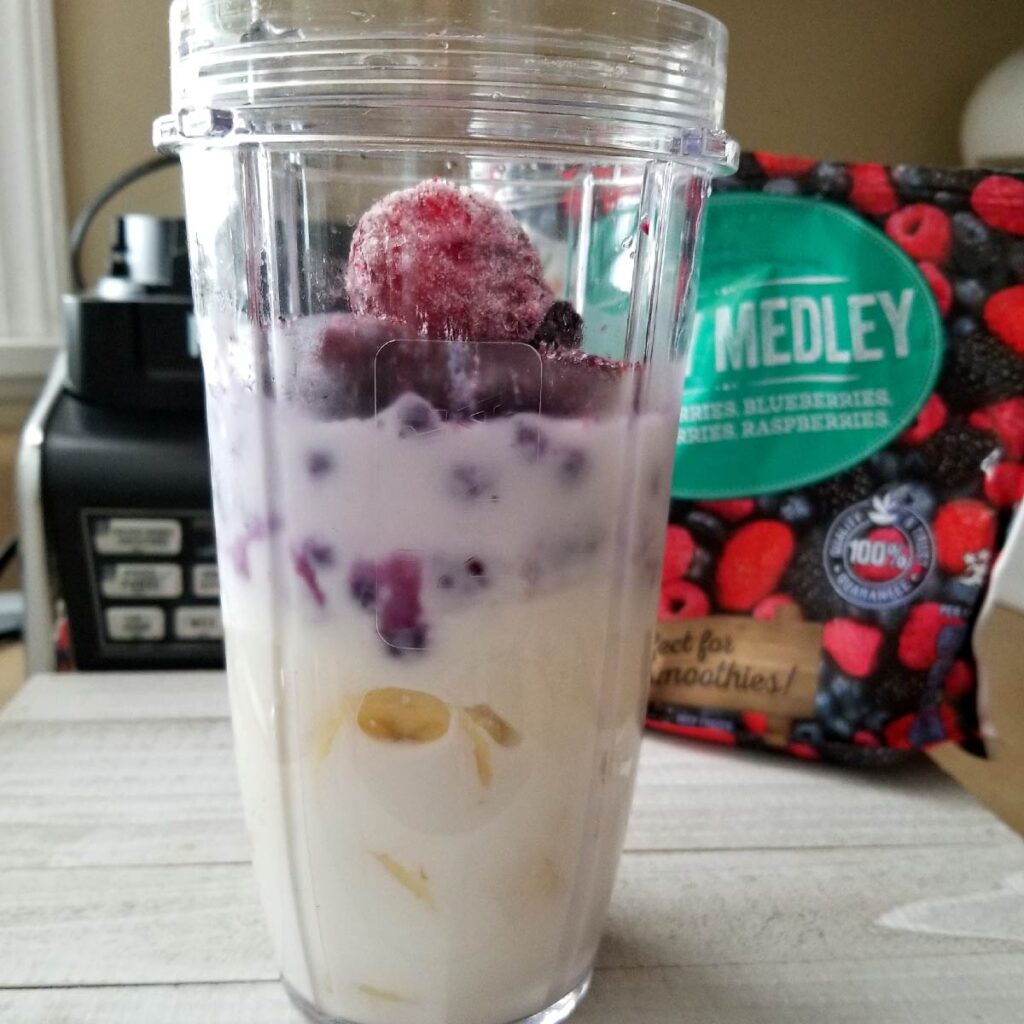 Layering the fruits, milk and yogurt in the smoothie cup