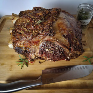 Rib roast sitting on a cutting board with a knife ready to be cut.