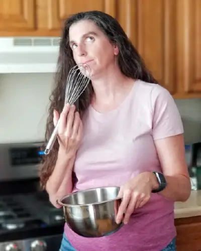 Dawn holding a whish and a stainless steel bowl.