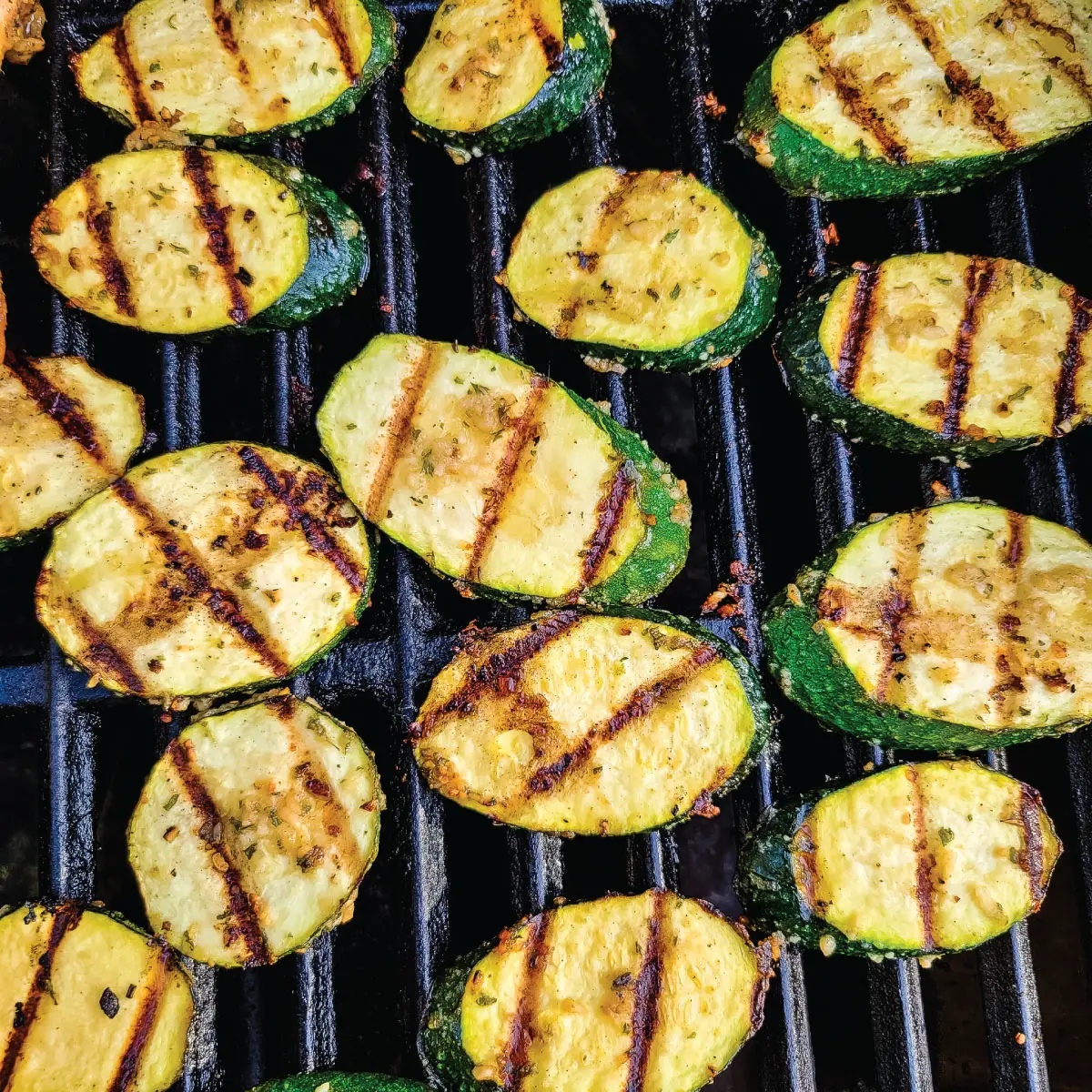 Zucchini slices on the grill after being flipped over once to show the sear marks.