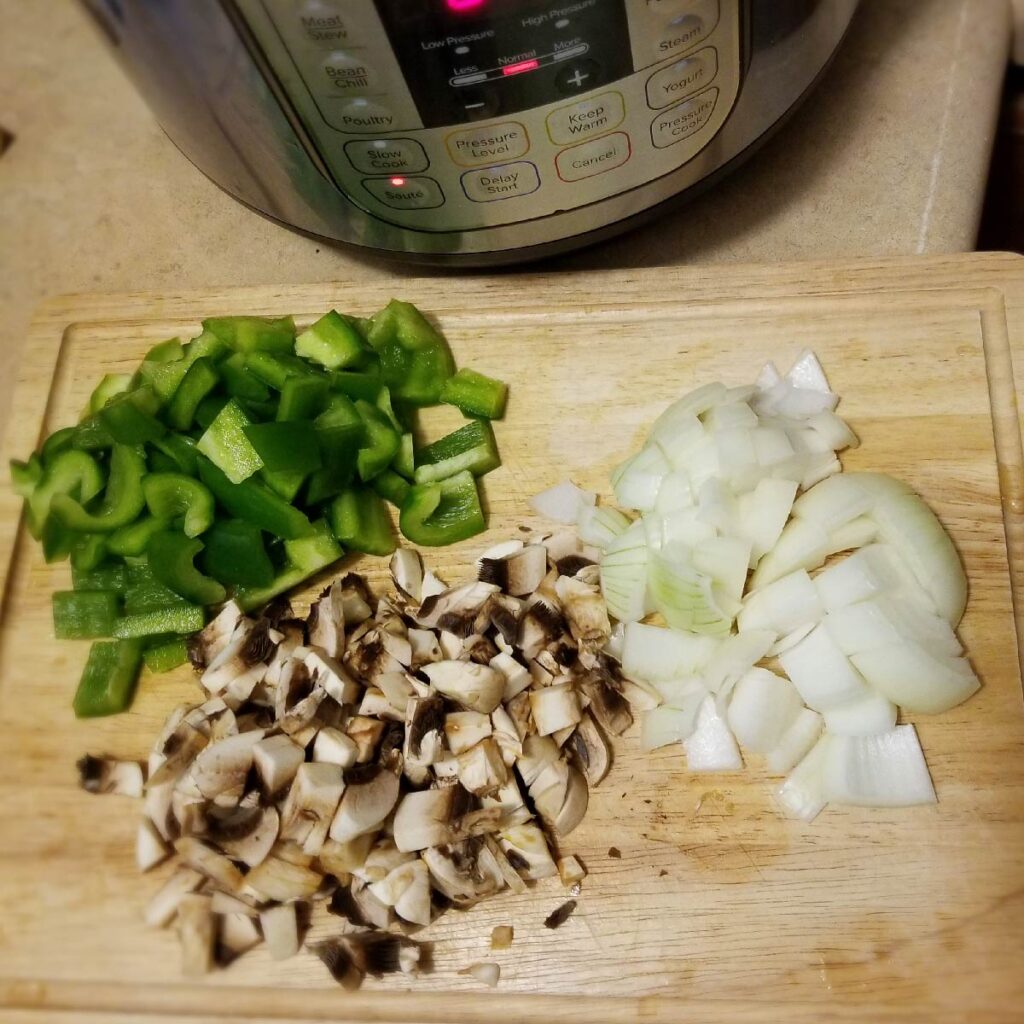 chopped peppers, onions and mushrooms on a cutting board ready to go into dinner