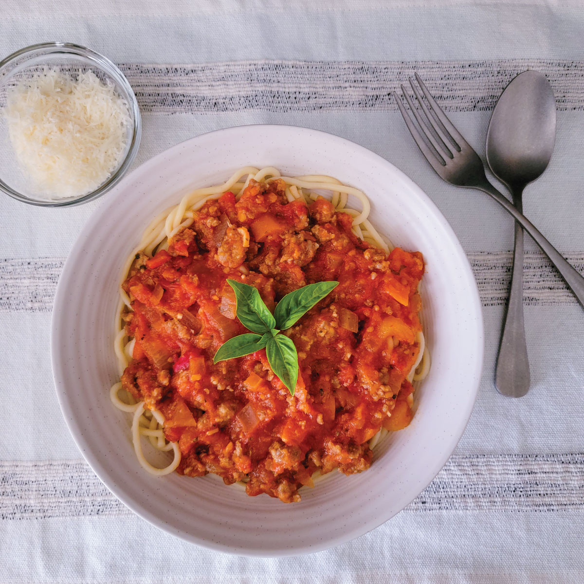 Pasta in a dinner bowl with pumpkin sauce and sausage on top.