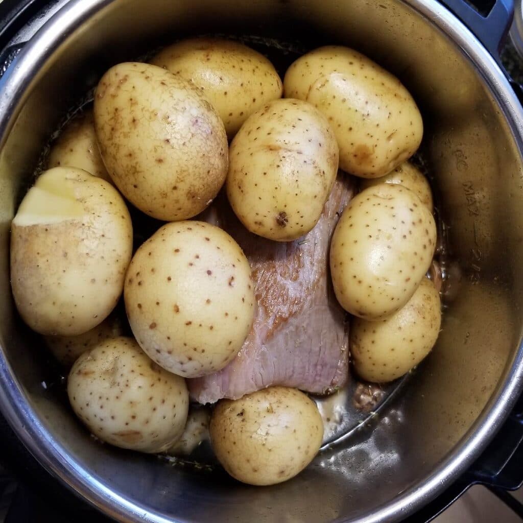 Potatoes layered on top of the roast and out of the broth so they cook evenly