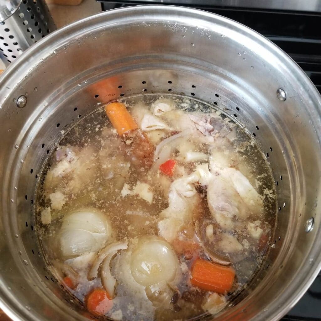 Chicken bones and vegetables covered in water for broth