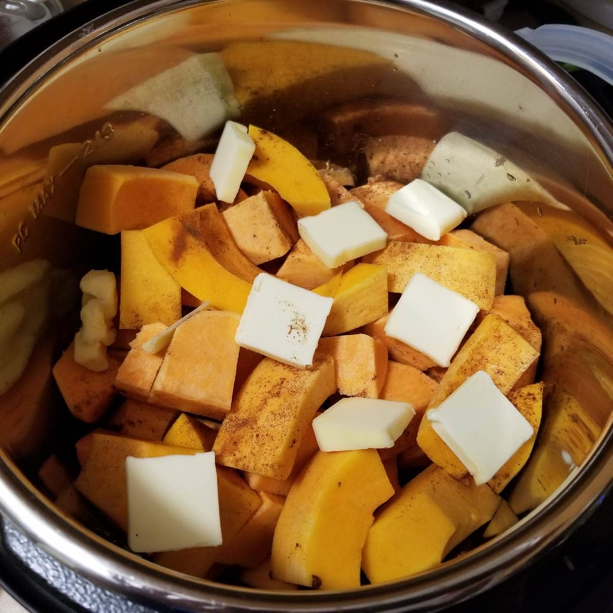 Butternut squash and sweet potatoes cut up into pieces with thin butter slices placed on top.  Nutmeg and cinnamon sprinkled on top.