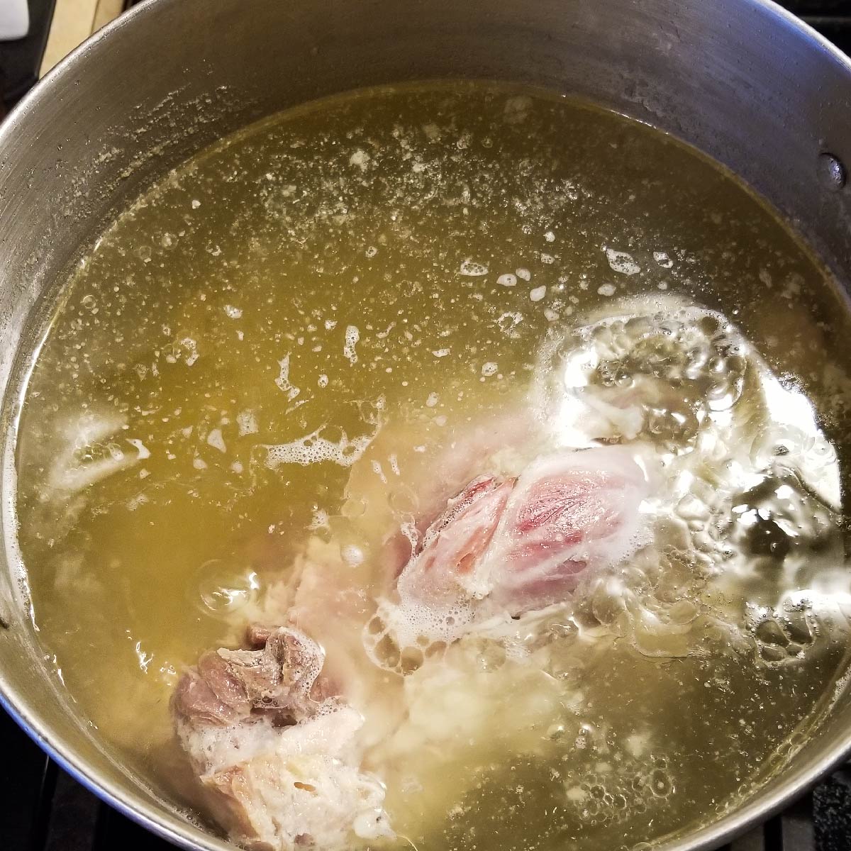 Ham bone boiling down in water in a large pot.