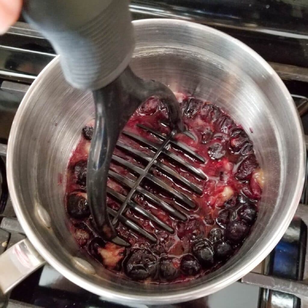 Mashing blueberries with a potato masher