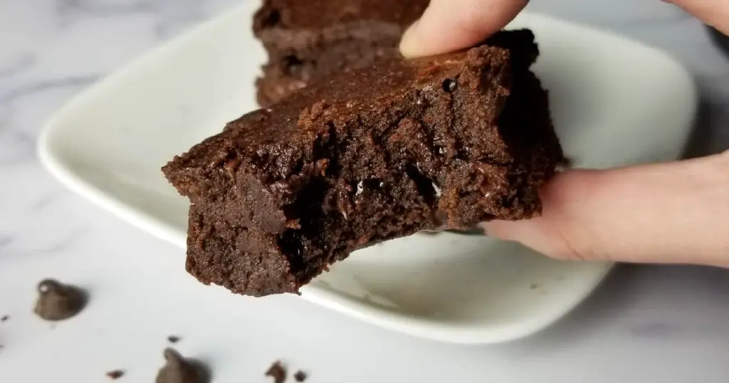A fudge brownie with a bite missing to show the fudgy texture