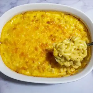 Macaroni and cheese in a baking dish ready to be served with a spoon scooping some out.