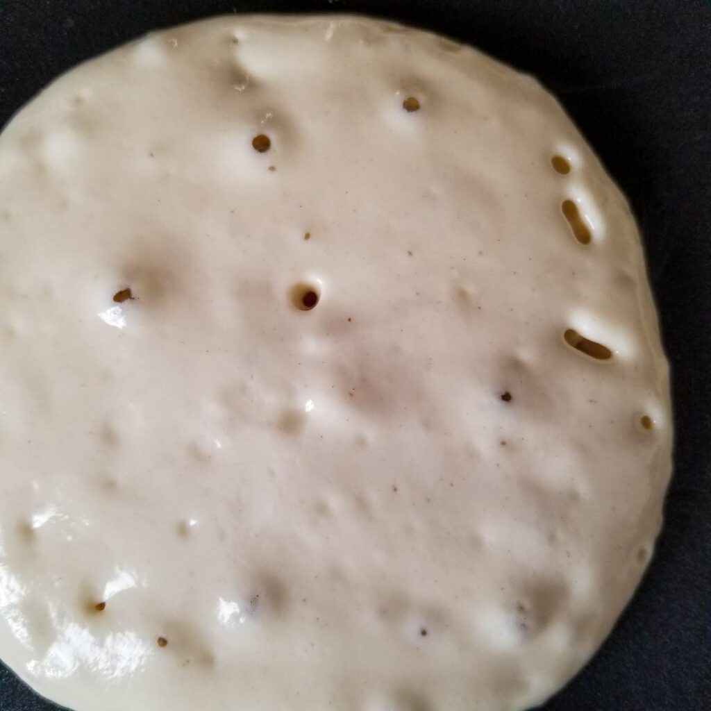 Pancake with tiny air bubbles that have popped, indicating it is time to flip.