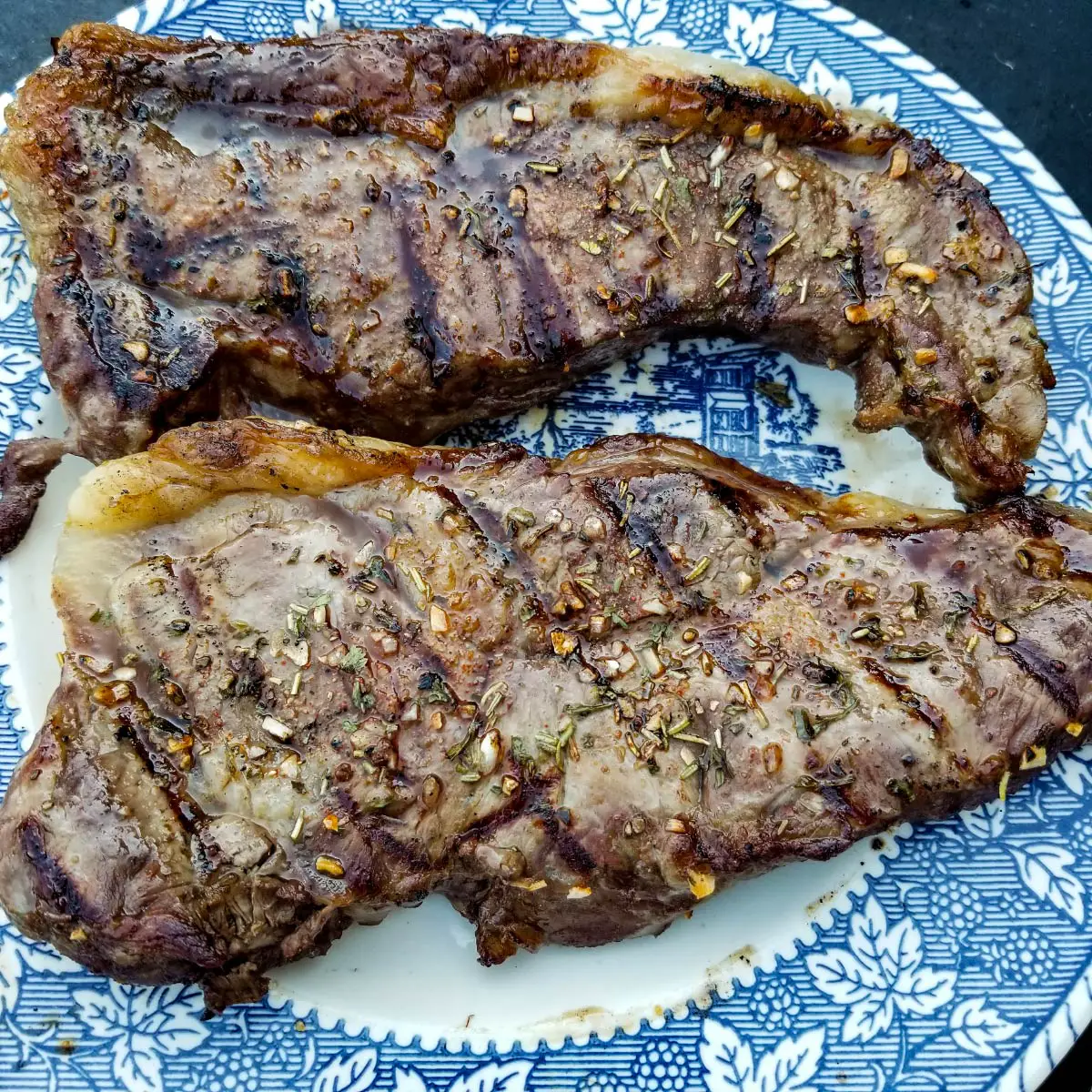2 strip steaks on a plate after being removed from the grill.