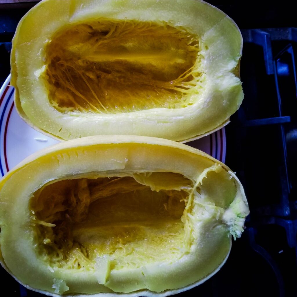 Spaghetti squash cut in half on a plate after being cooked