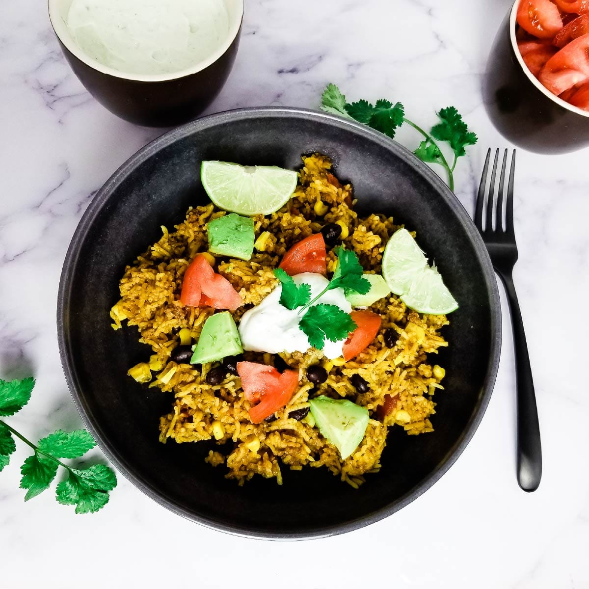 Taco rice in a dinner bowl with veggies and a sour cream topping.