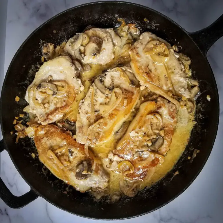 pork chops in a frying pan with mushrooms on top ready to be served