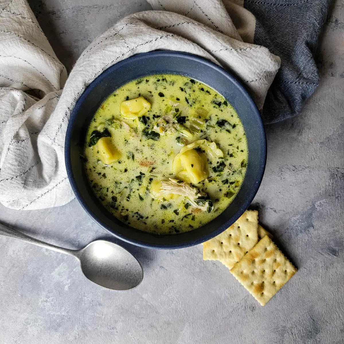 Tortellini soup in a bowl ready to be served with crackers.