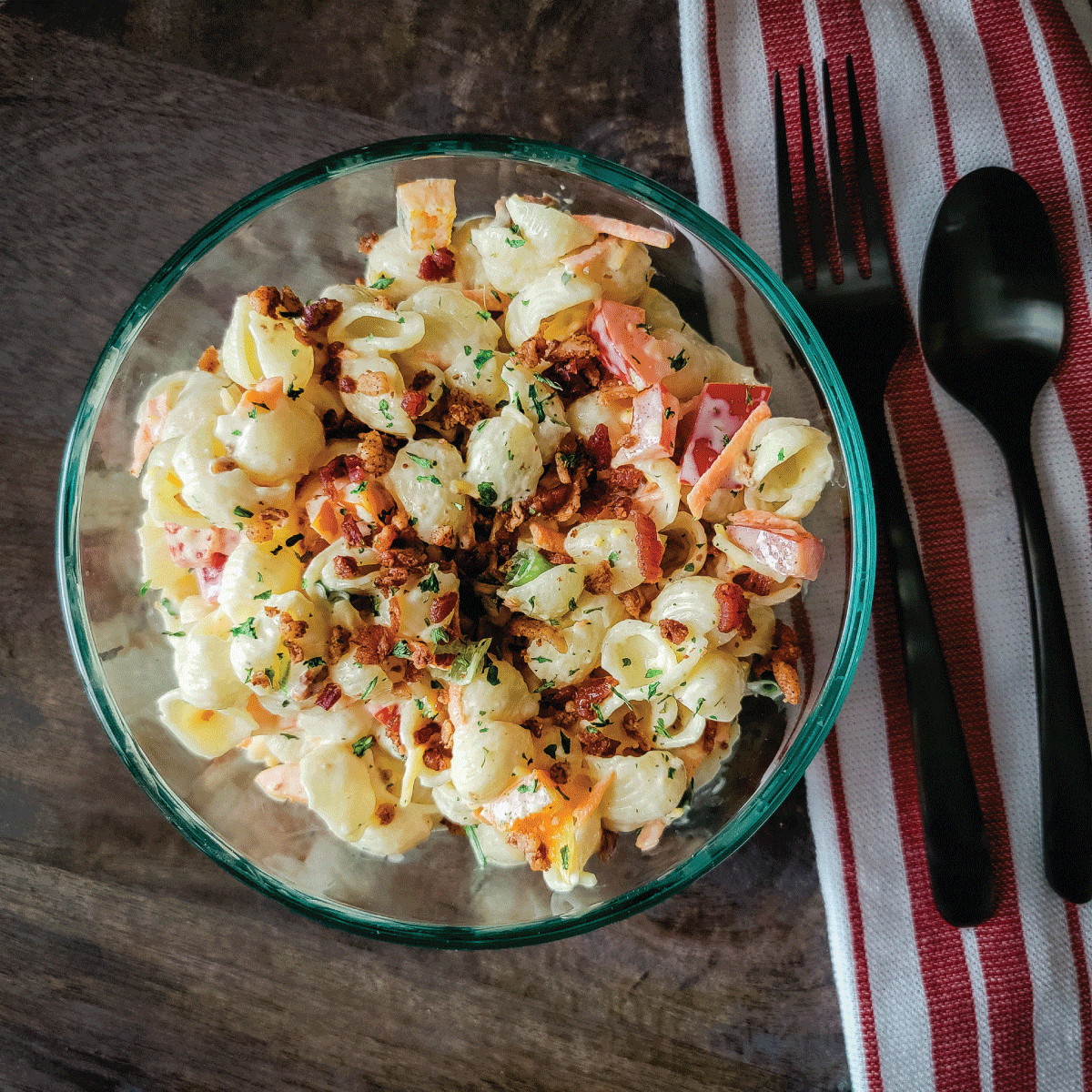 pasta salad in a serving bowl topped with bacon