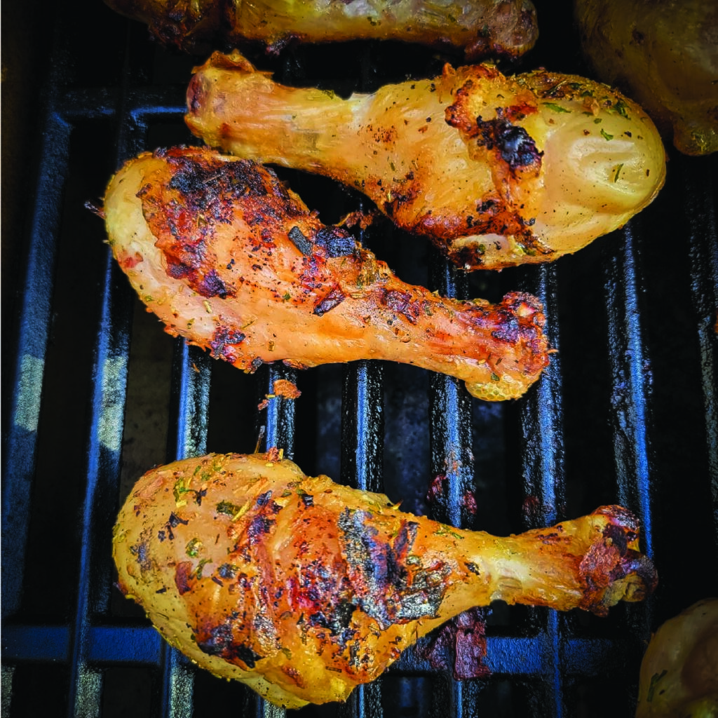 chicken legs on the grill with a crispy skin just before coming off to serve