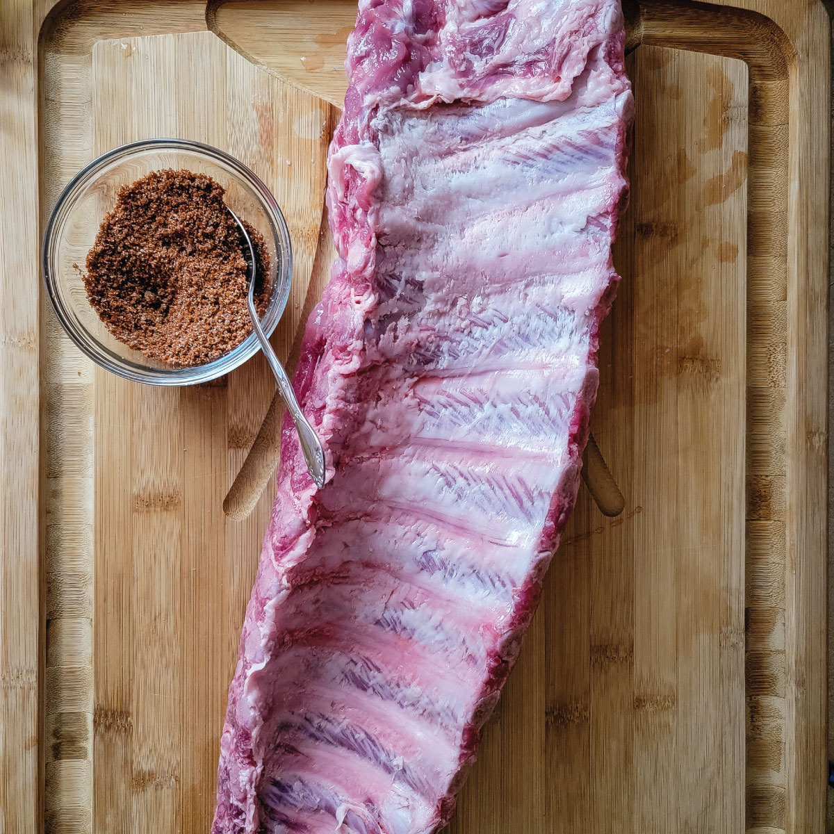 Rack of ribs on a cutting board after removing membrane before dry rub.