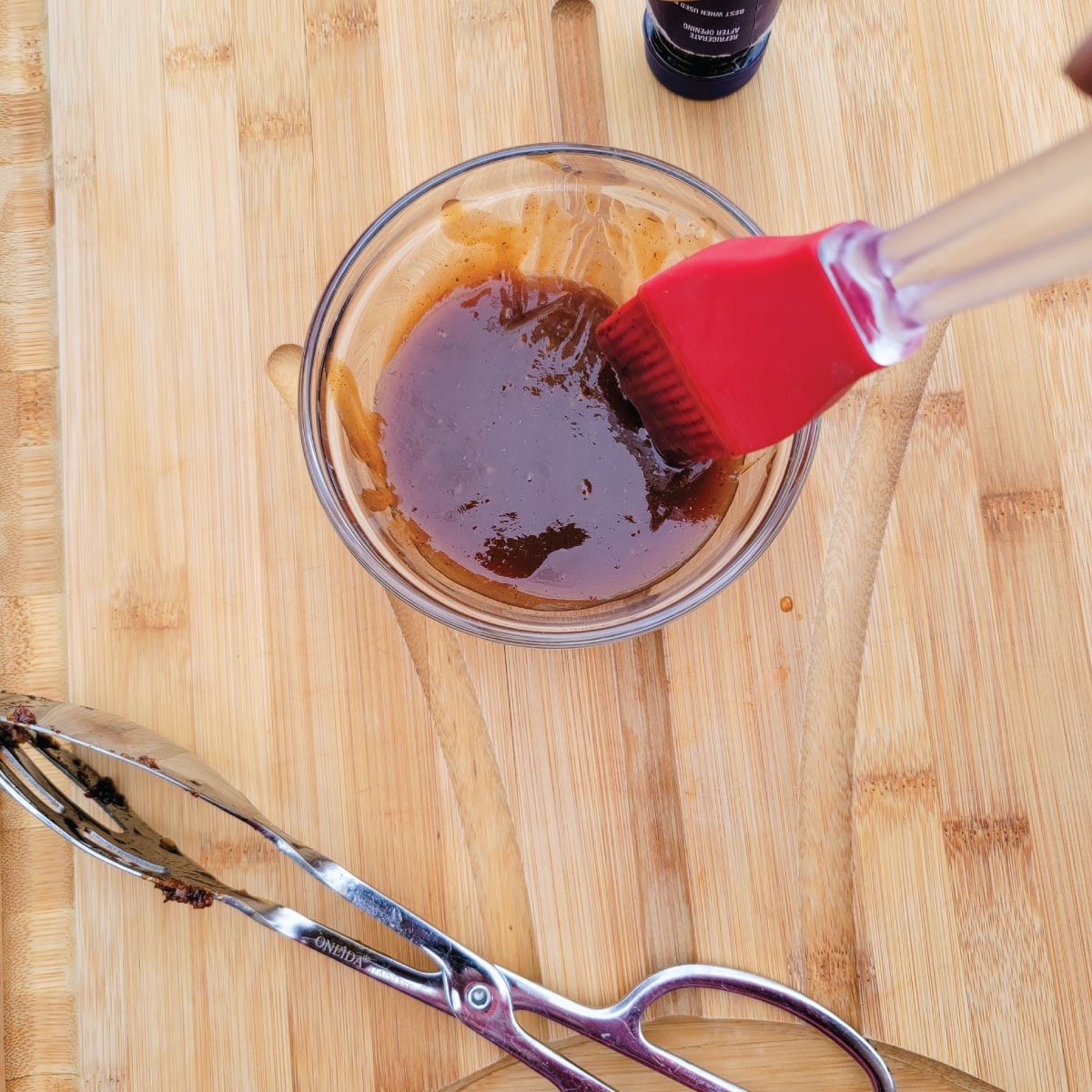 BBQ sauce in a prep bowl with a silicone basting brush in it.