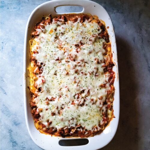 Baked spaghetti casserole in a baking dish after coming out of the oven ready to serve.