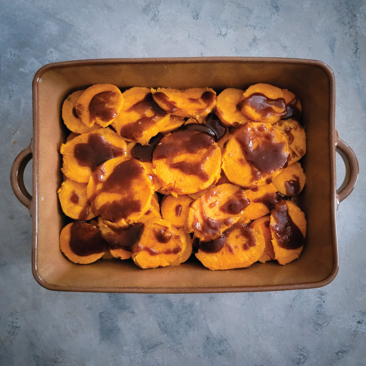 Adding the butter and brown sugar mixture to the top of the sweet potatoes.