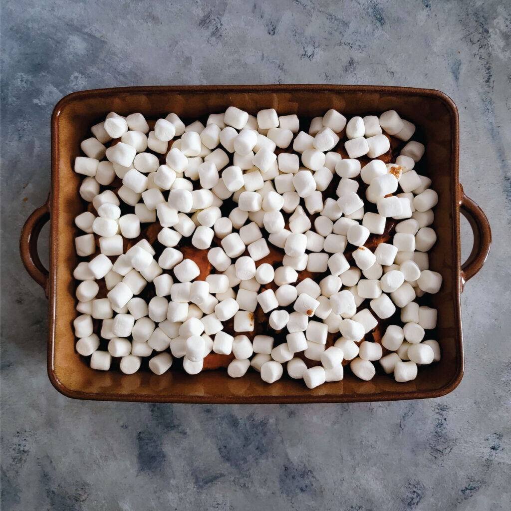 Adding the marshmallows to the top of the casserole.