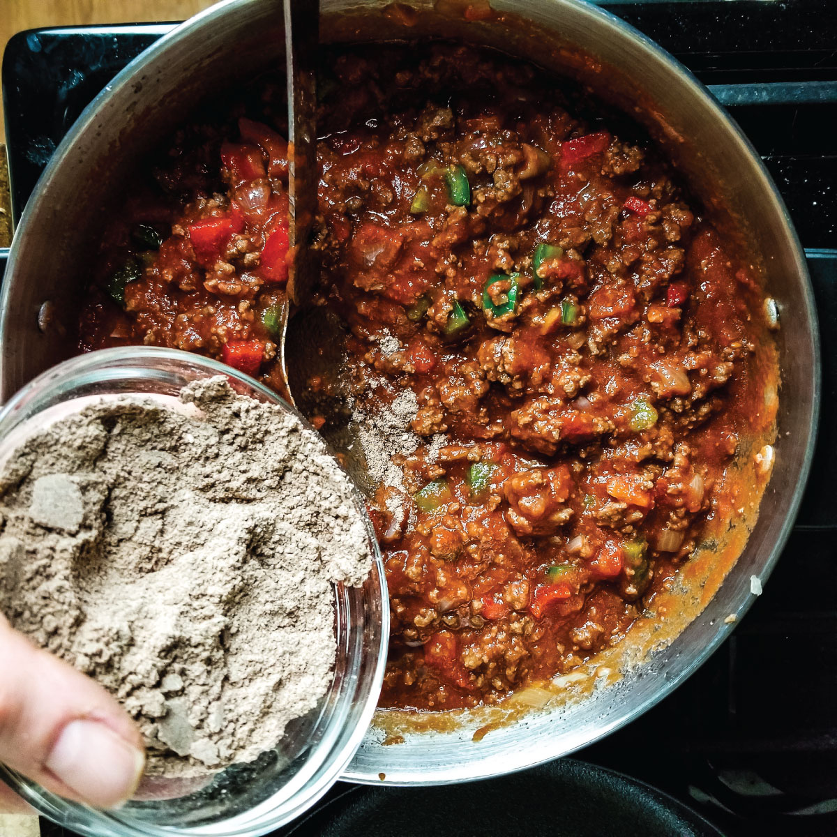 Adding seasoning mix to the chili in a large pot.