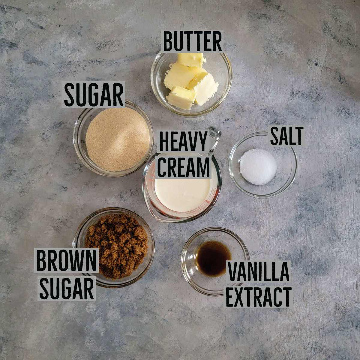 Ingredients for salted caramel in prep bowls - butter, salt, vanilla extract, brown sugar, sugar and heavy cream.