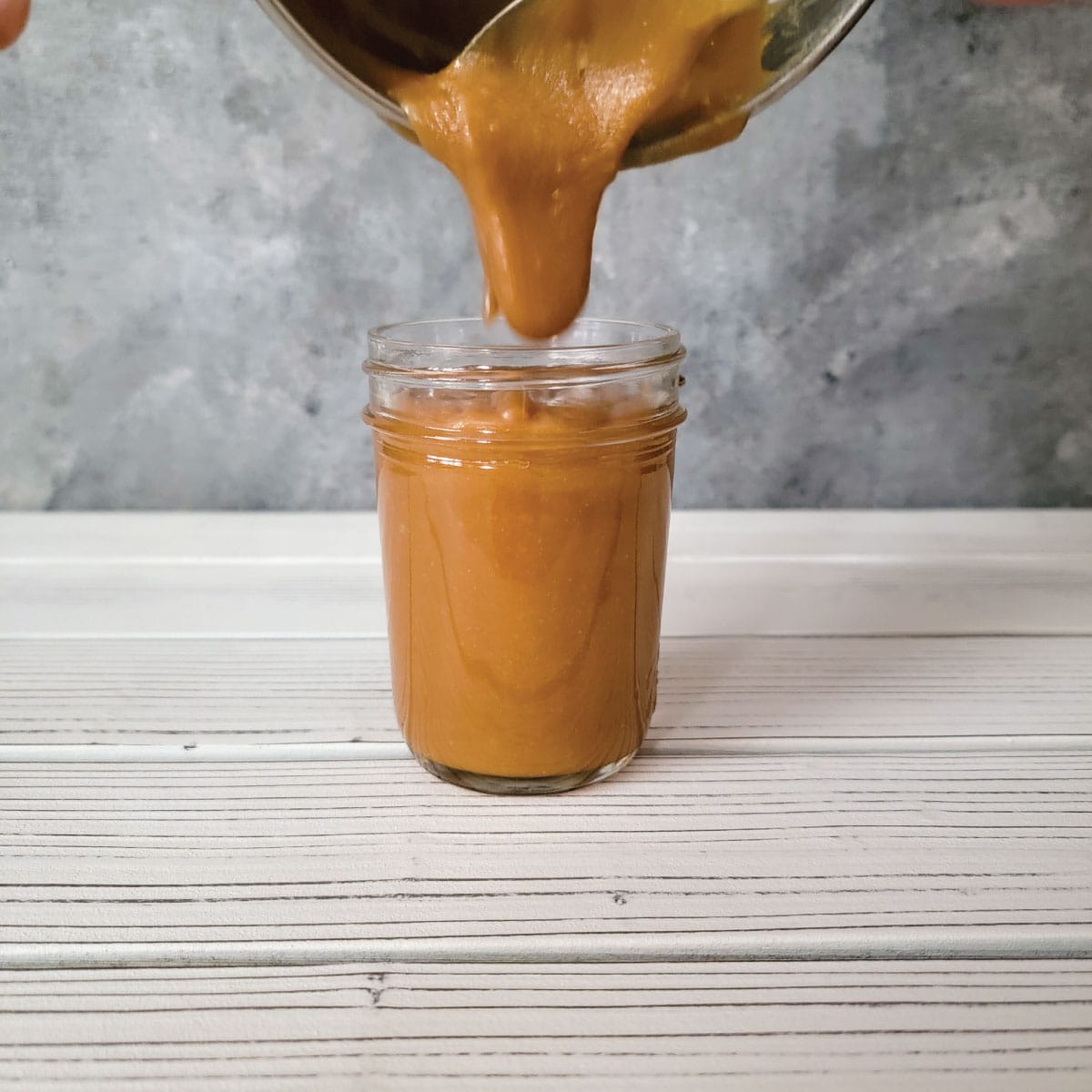 Caramel that is too thick being poured into a jar to demonstrate what is too thick.