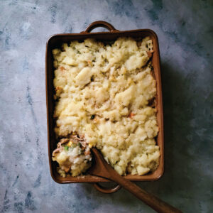 Turkey casserole in a baking dish out of the oven with a spoon scooping it out to serve.