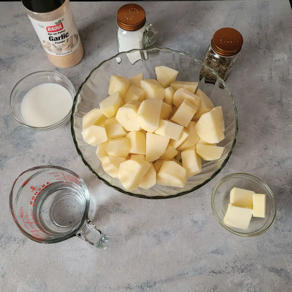 Ingredients for mashed potatoes - potatoes, butter, milk, water, salt, pepper and garlic.