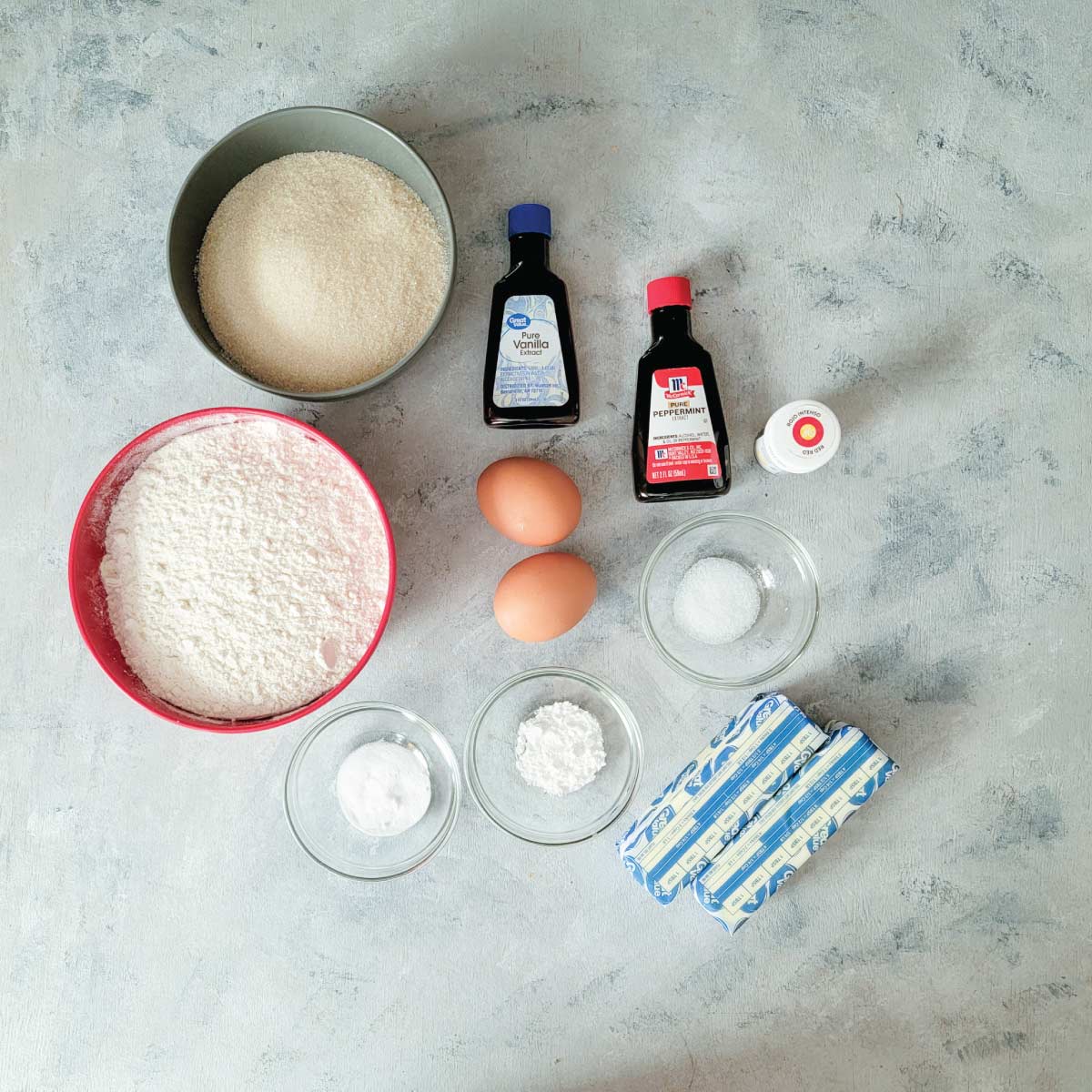 Ingredients prepped for the cookies - sugar, vanilla extract, peppermint extract, food coloring, baking soda, baking powder, salt, butter, flour and eggs.