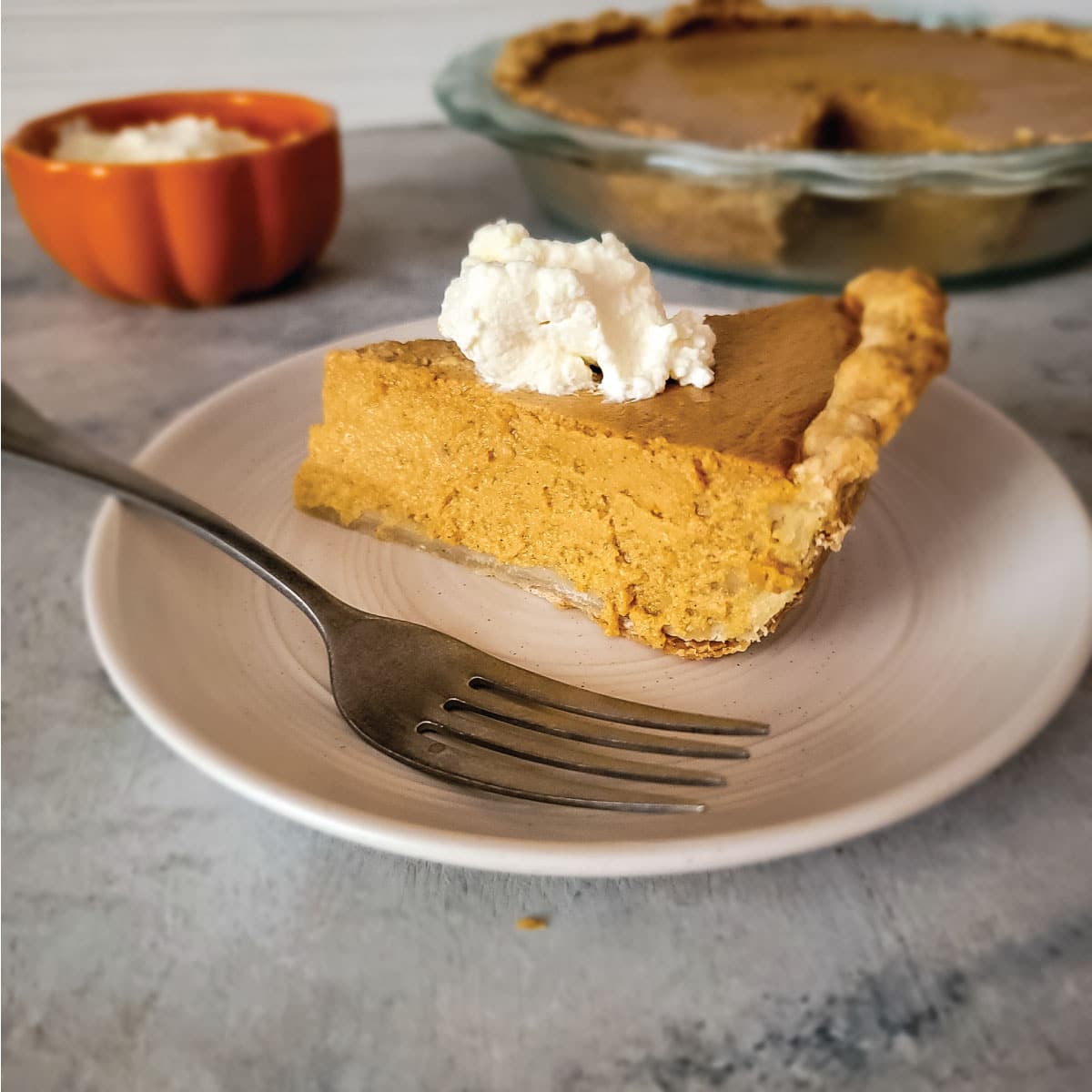 Slice of pie on a plate topped with whipped cream ready to serve.