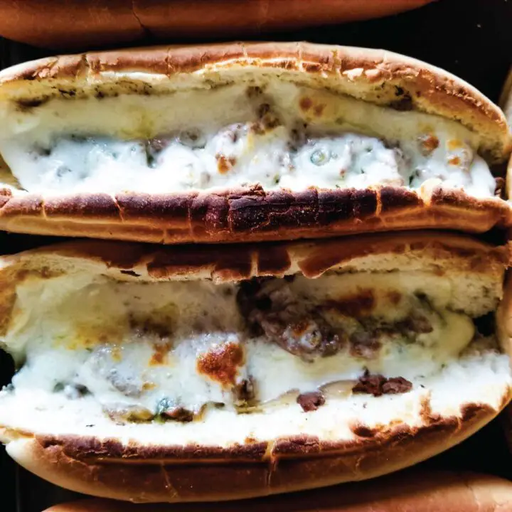 Cheesesteaks with melted cheese and toasted buns after coming out of the broiler.
