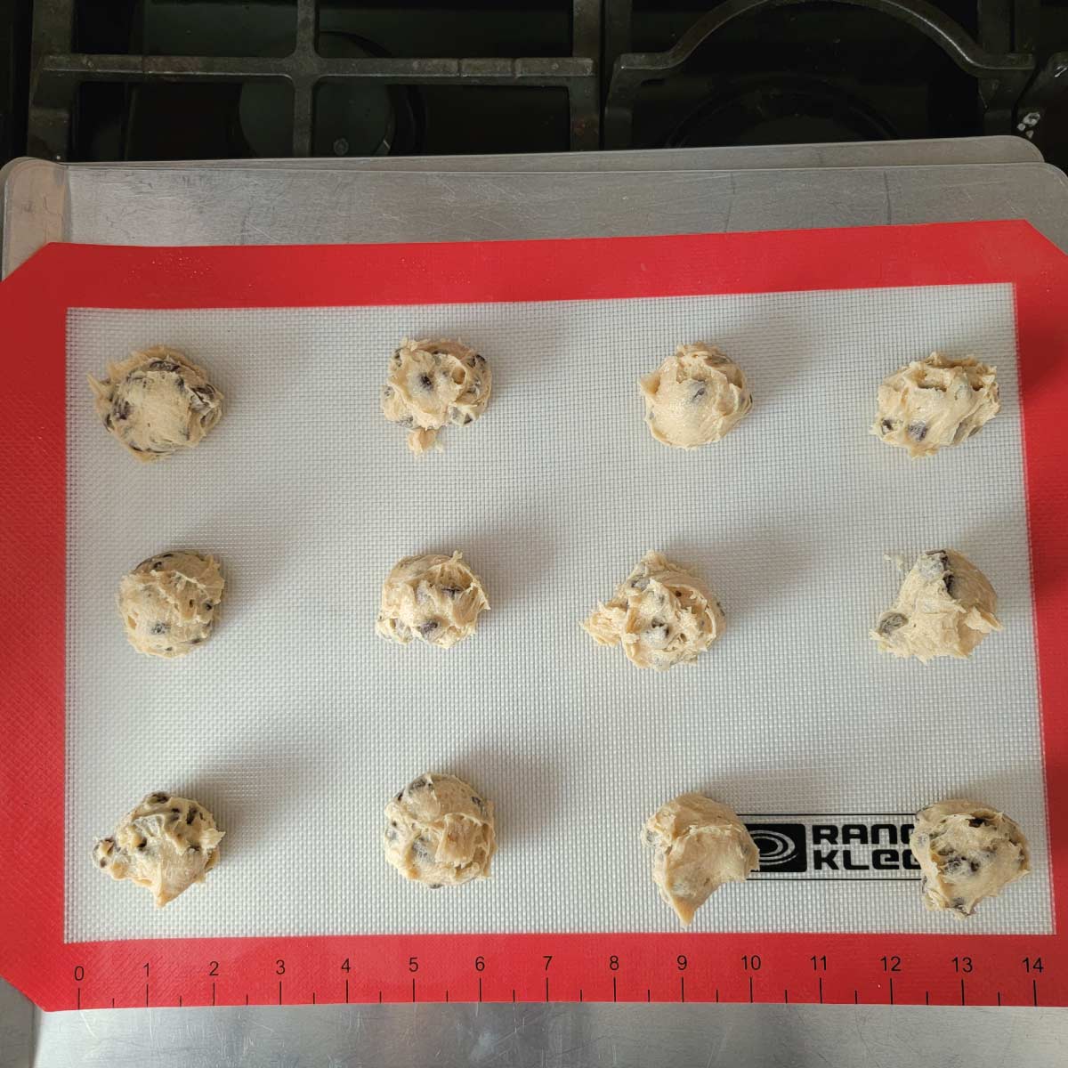 Cookie dough balls on a silicone baking mat ready to go in the oven.