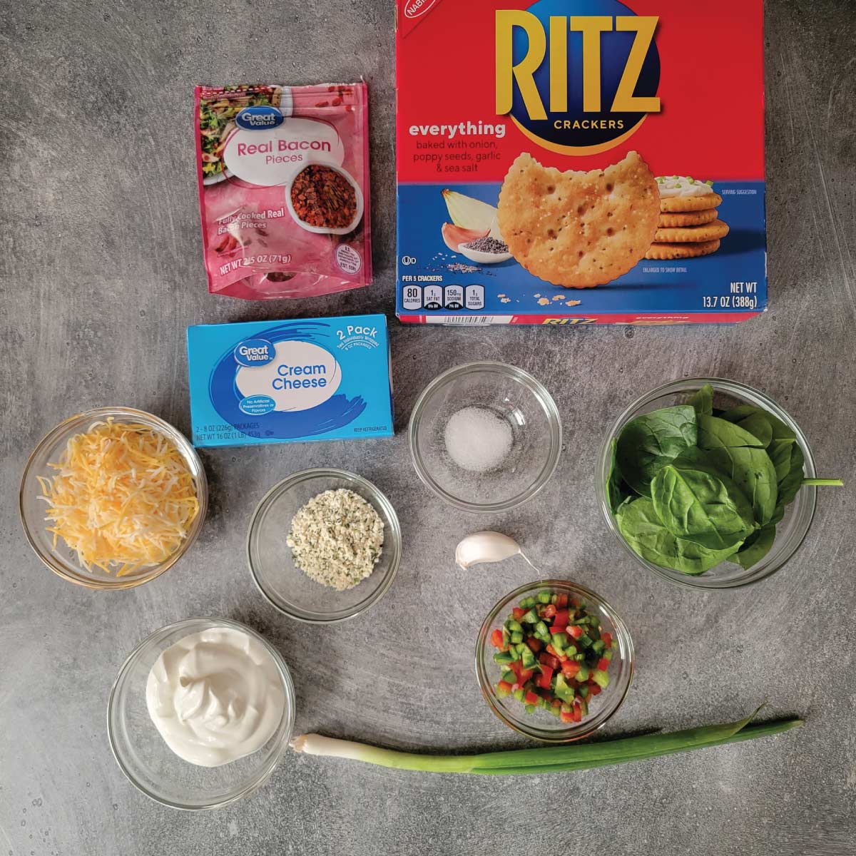 Ingredients for cheeseballs - real bacon pieces, Ritz crackers, cream cheese, salt, spinach, chopped red and green peppers, garlic clove, ranch seasoning, shredded cheese, sour cream and 1 scallion.