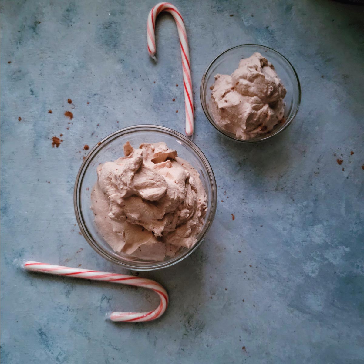 2 bowls with whipped cream in them and 2 candy canes by the bowls for decoration.