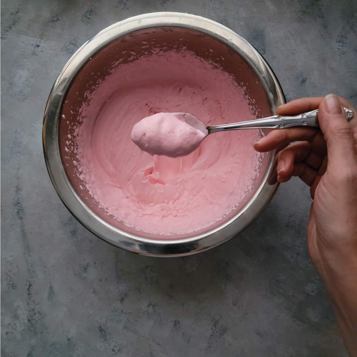 Whipped cream in a bowl with a spoon scooping out some to serve.