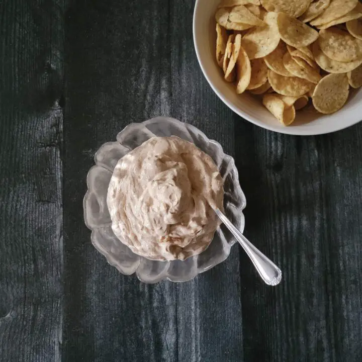 Dip prepared and in a small serving bowl with a bigger bowl of tortilla chips next to it.