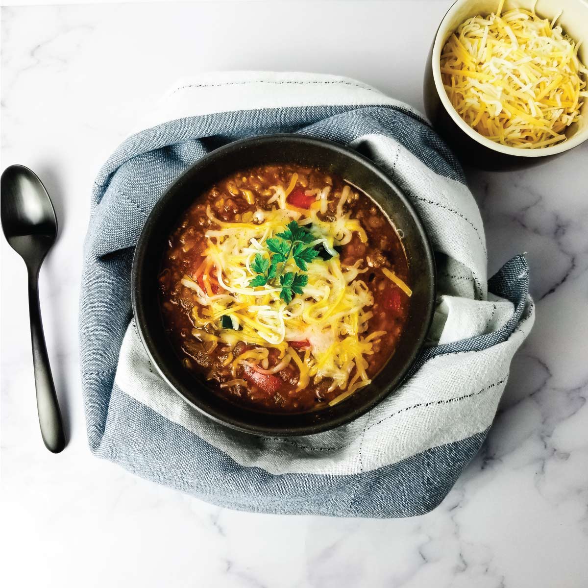 Bowl of stuffed pepper soup with cheese melted on top and garnished with fresh parsley.