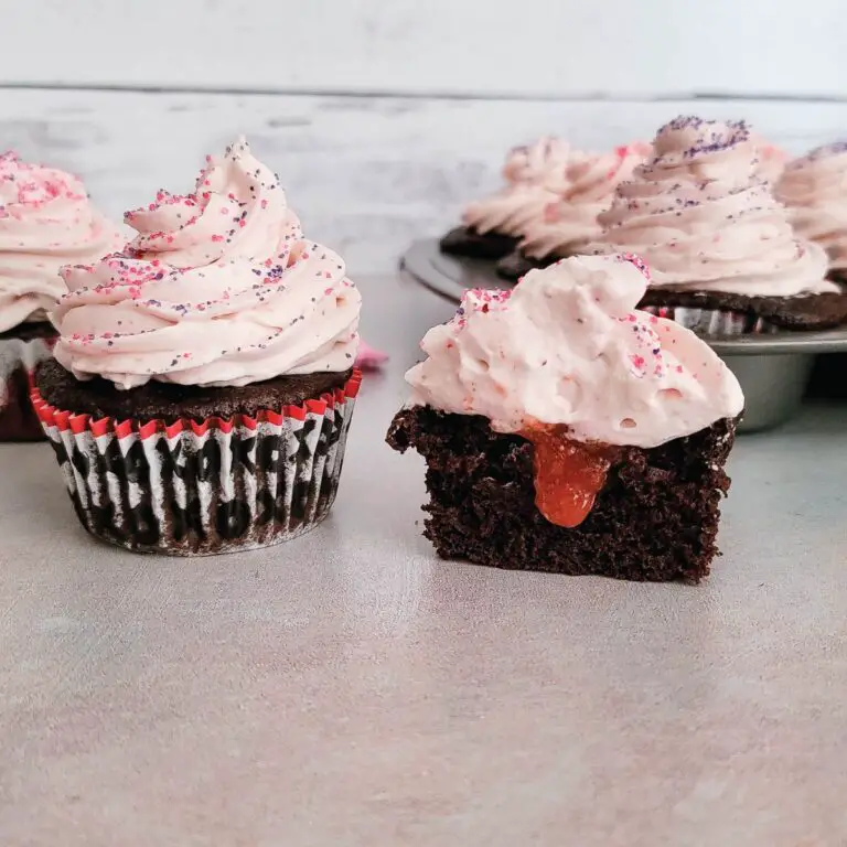 Chocolate cupcakes with one cut in half to show strawberry filling in the inside.
