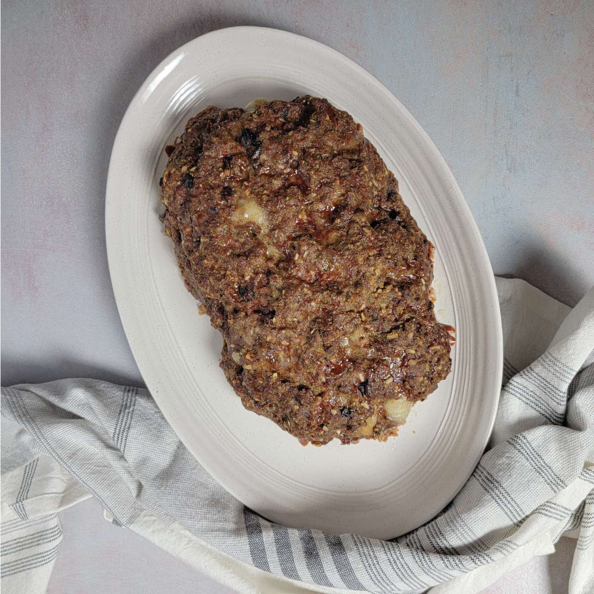 Meatloaf stuffed with cheese on a platter resting before cutting.