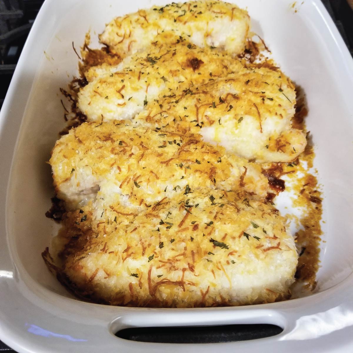 Chicken with a potato and cheese topping in a baking dish resting before serving.