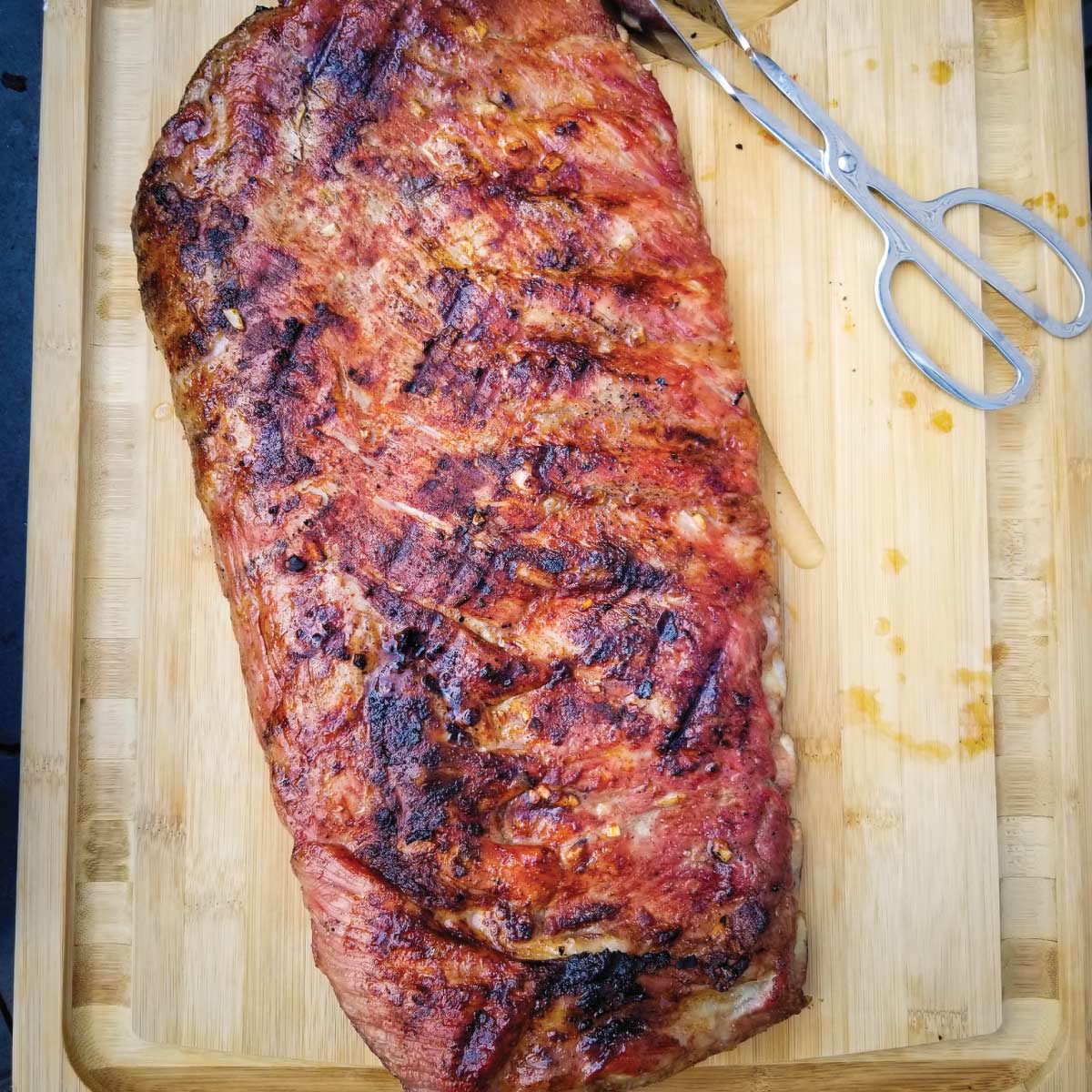 Rack of St Louis ribs resting on a cutting board after cooking.