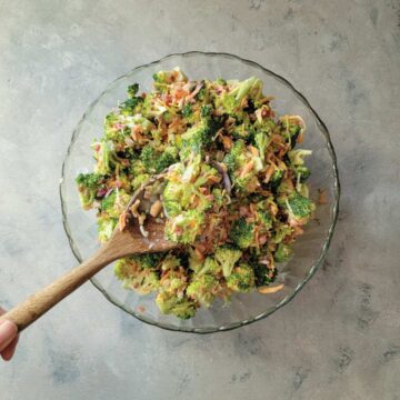 Broccoli salad in a bowl ready to serve with a spoon scooping some out of the bowl.