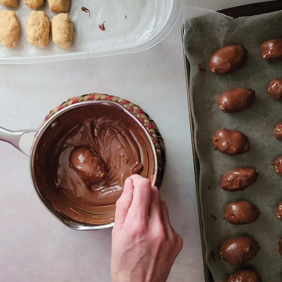 Egg in melted chocolate in a small sauce pot being coated in chocolate.