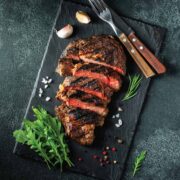 Steak on a stone cutting board sliced with spices around it as decoration.