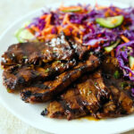 Steak on a plate ready to serve with some shredded cabbage and carrots.