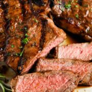 Steak on a plate and a couple slices were cut showing a medium rare doneness.